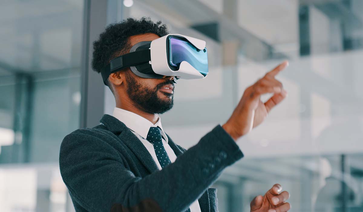 A man uses a virtual reality headset in an office environment. Learn more about this and other LMS trends.