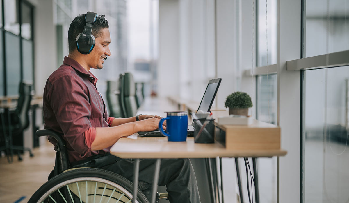 A male employee in a wheelchair takes an online training course at work. Discover how an LMS can make training more cost-effective for your team.