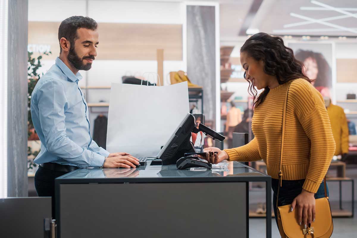 A woman making a purchase at a retail store with the assistance of an employee.